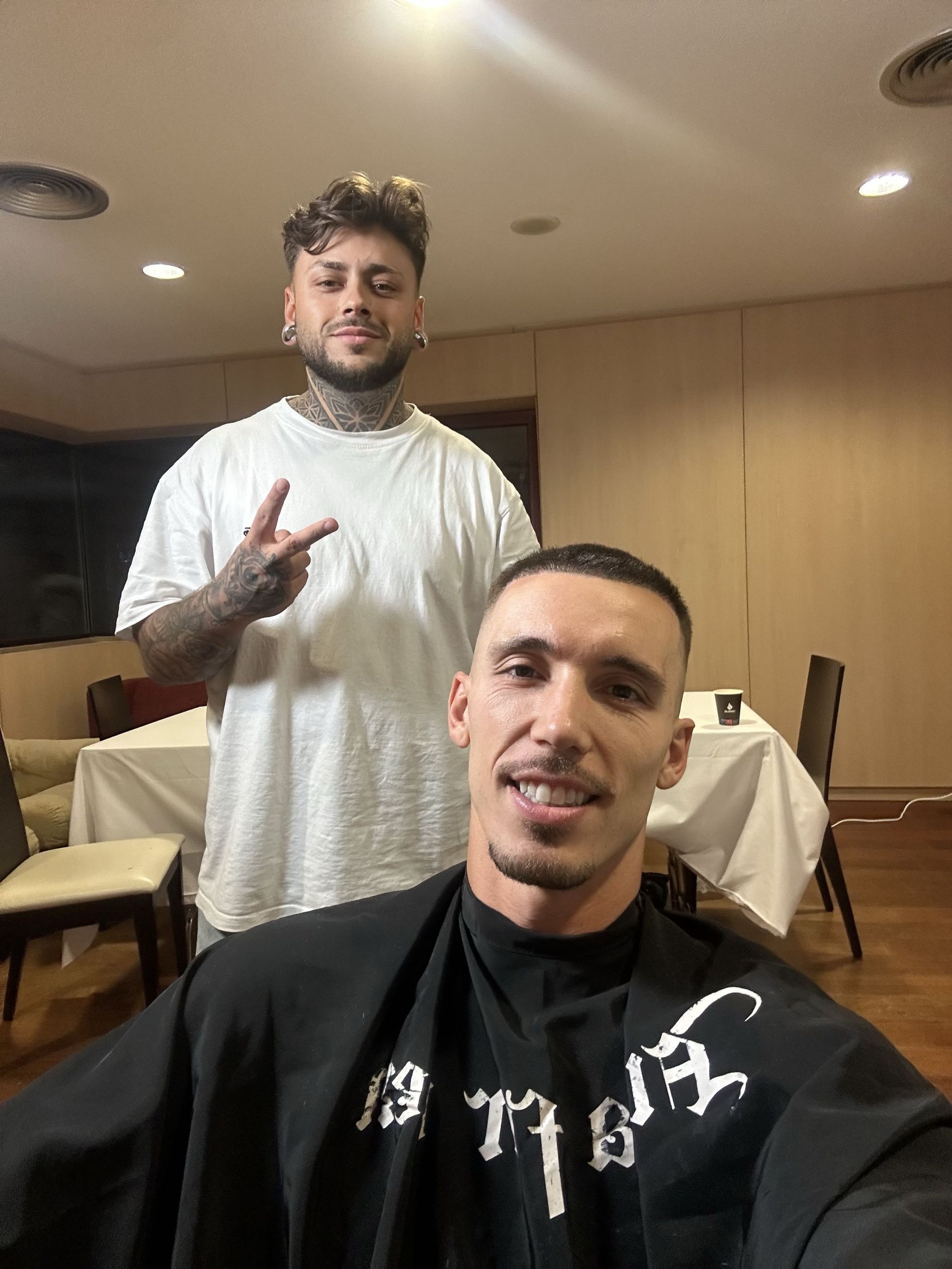 Barbero y cliente mostrando el resultado de un corte
